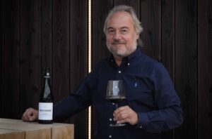 Man with a glass of wine in front of a wooden cladding