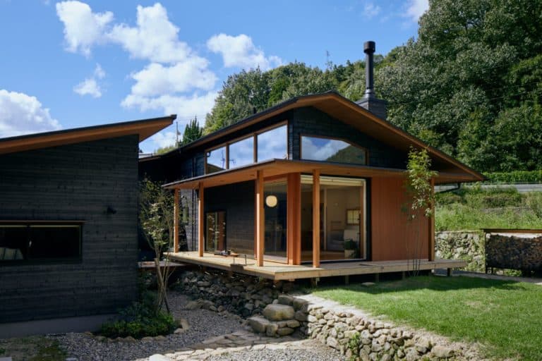 Building with black facade wood and large glass fronts surrounded by trees